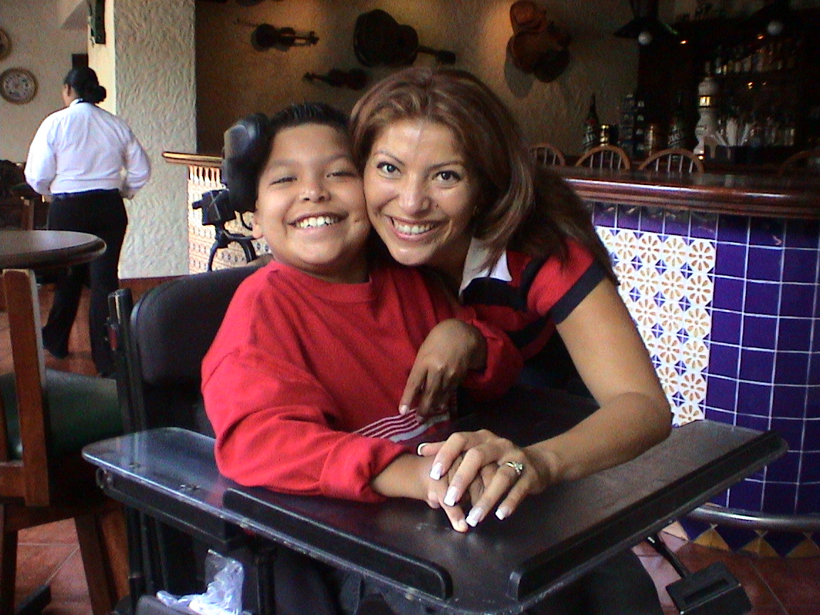 Raul as a child smiling with his mom Debbie at a restaurant